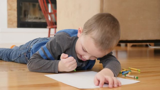 A dolly shot of an adorable little boy coloring on the floor