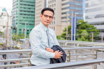 Asia young business man in front of the modern building in downtown .Concept of young  business people