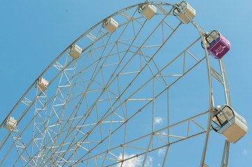 White fluffy clouds in deep blue sky, big Ferris wheel on sky background