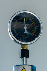 Pressure gage on an industrial press with a greasy look suggesting workshop tools