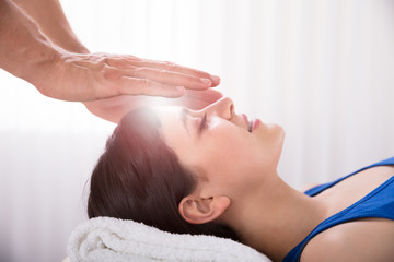 Obraz na płótnie Canvas Therapist Performing Reiki Healing Treatment On Woman