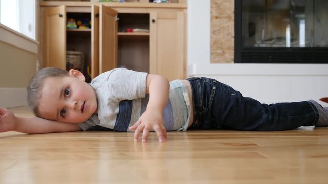 A dolly shot of little boy lying on the floor in a house