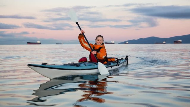 Cinemagraph of a woman enjoying the beautiful ocean scenery on a sea kayak during a vibrant sunris. Taken near Jericho Beach, Vancouver, British Columbia, Canada. Still image continuous loop animation