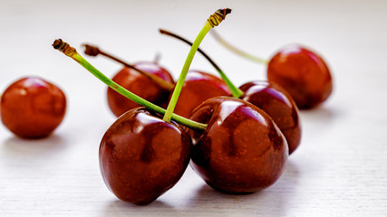Red cherries on a white spoon and white background.