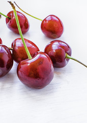 Red cherries on a white spoon and white background.