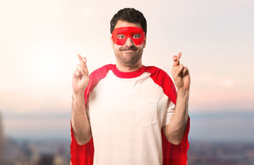 Superhero man with mask and red cape with fingers crossing and wishing the best. Making a wish. on...