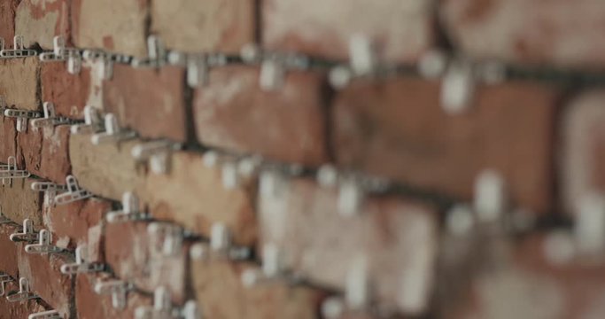 Slow motion focus pull of brick cuts tile on the wall