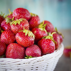 Ripe red strawberries in white basket  on  gray background.