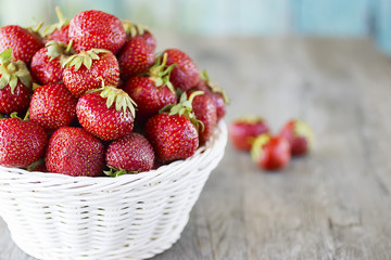 Ripe red strawberries in white basket  on  gray background.