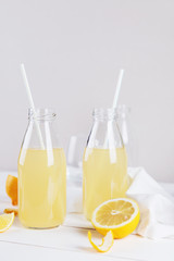 Glass bottles of fresh summer detox lemonade with lemon on a light background. Space for text.