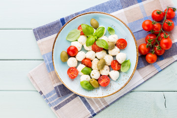 Delicious caprese salad with ripe cherry tomatoes and mini mozzarella cheese balls with fresh basil leaves.