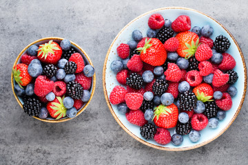 Fresh berry salad on blue dishes. Vintage wooden background.
