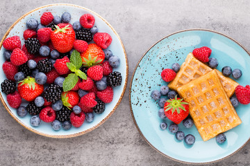 Fresh berry salad on blue dishes. Vintage wooden background.