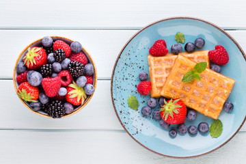 Fresh berry salad on blue dishes. Vintage wooden background.