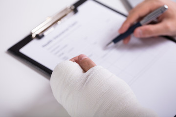 Person With Fractured Hand Filling Health Insurance Form