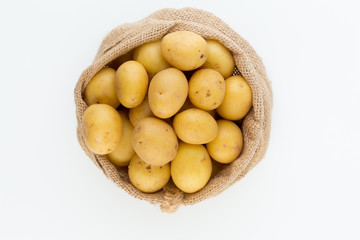 Sack of fresh raw potatoes on wooden background, top view