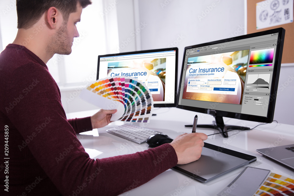 Poster Designer Working On Multiple Computer Screens