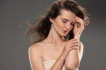 brunette tender woman with closed eyes in bra, isolated on grey