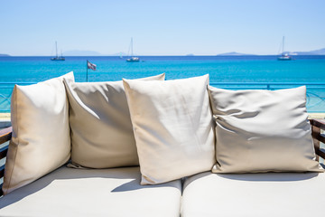 Resort, Greece, Kos Island, Kefalos: relaxing by the sea on a cozy couch with little pillows right near the greek coast with crystal clear water, some boats sail and listen to the sound of the waves