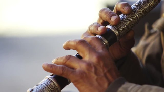 people celebrate the beginning of spring, man playing on music instruments, close-up detail fingers on flute