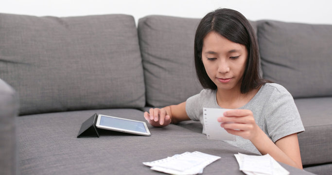 Woman record the daily expense of tablet computer at home