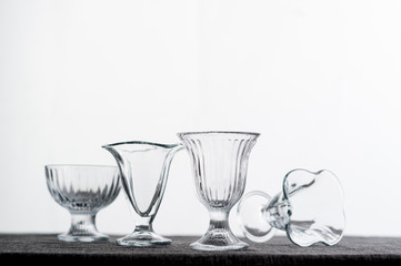3 Clean glass bowls for ice cream, with different texture, are on the table with a gray tablecloth