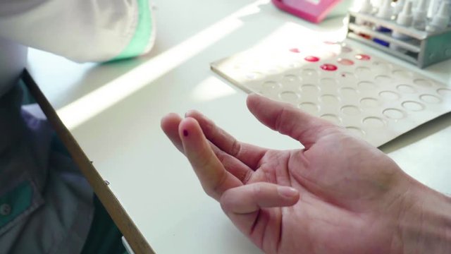 Finger blood test. Closeup of hands in glove taking blood sample. Close up of blood testing. Nurse drawing blood from male hand. Medical test hiv