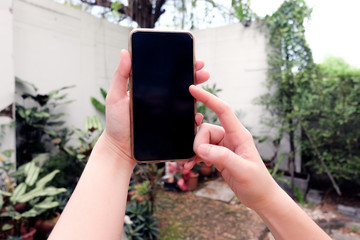Hand holding a smart phone with black screen on natural background.