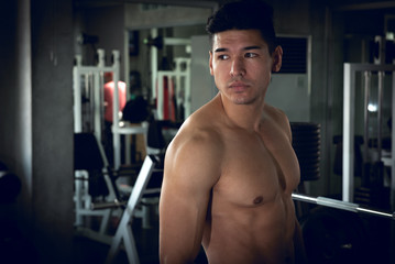 Portrait of sport young fitness man with white towel on his neck, relax after exercise at indoor sport gym, healthy sport concept.