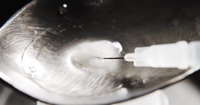 Top view of filling syringe with heroin from a spoon