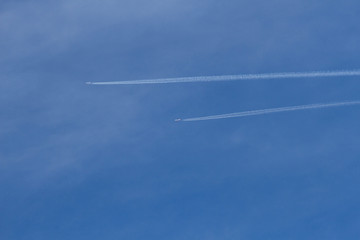 Dos aviones  dejando estela o rastro en un cielo azul con nubes ligeras