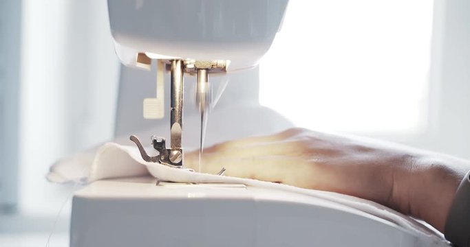 Slow motion shot of woman sews on sewing machine