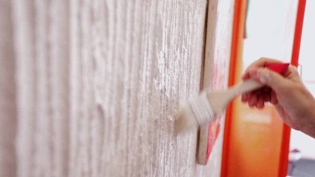 Woman holding paint brush, painting indoor wall, steadicam, close-up, slow motion