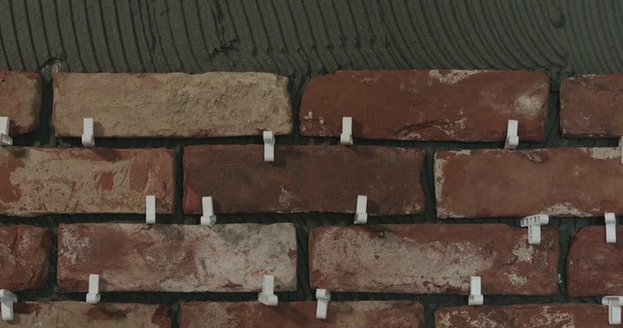 Slow motion pan of brick cuts tile on the wall