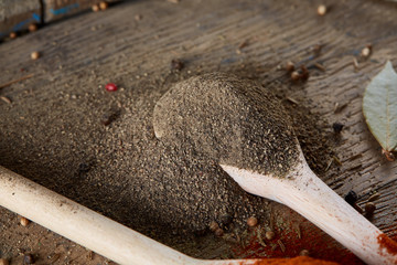 Top view of a wooden spoons full of paprica and black pepper on wooden barrel background, selective focus.