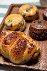 closeup delicious sausage bread roll and fresh tasty scones on wooden table