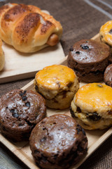 closeup delicious sausage bread roll and fresh tasty scones on wooden table