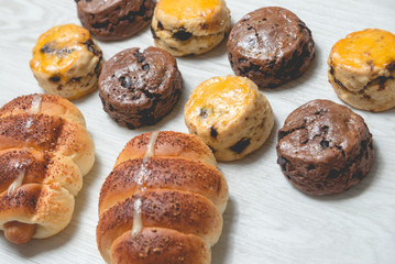 closeup delicious sausage bread roll and fresh tasty scones on wooden table