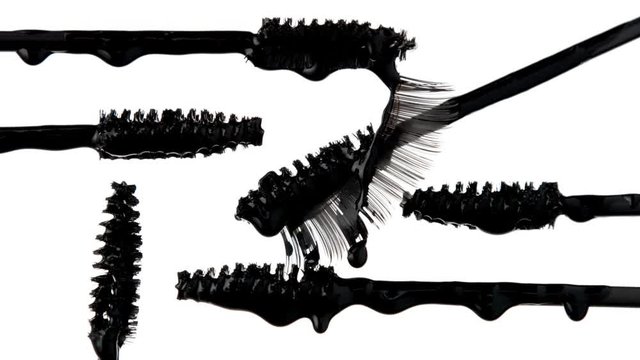 mascara brushes with drops of liquid mascara on it and a falce lashes. Cosmetics closeup macro texture