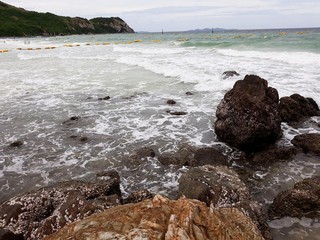 pebble stones on the sea beach, the rolling waves of the sea with foam