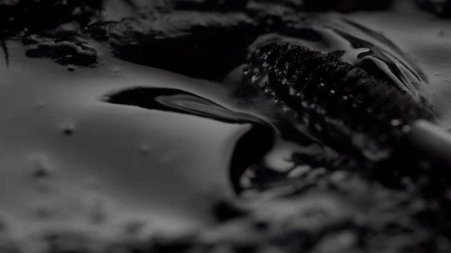 black liquid texture and mascara brush moving this liquid closeup cosmetics texture
