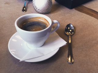 Breakfast in the cafe. Cup of Americano coffee in white mug, saucer and spoon. Close-up photo.