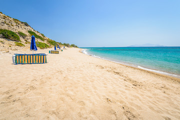 Beaches, Greece, Kos Island, Cap Helona: beautiful holiday setting on a secluded beach with umbrellas on the Greek Aegean Sea with turquoise waters and a picturesque bay and islands in the background
