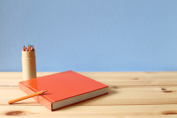 Notebook and colored pencil on wooden desk