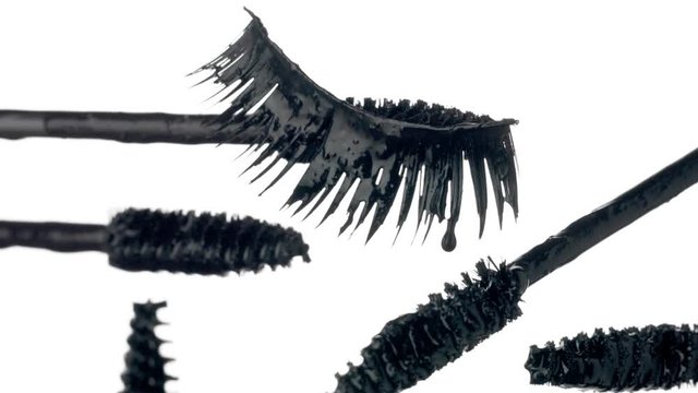 mascara brushes with drops of liquid mascara on it and a falce lashes. Cosmetics closeup macro texture Falling falce lashes