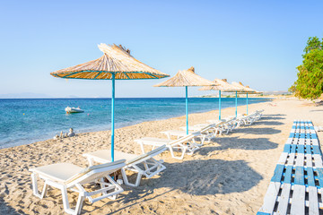 Beaches, Greece, Kos Island, Kardamena: beautiful holiday setting on a secluded beach with umbrellas on the Greek Aegean Sea with turquoise waters and a picturesque bay and islands in the background