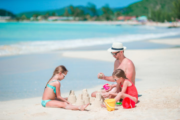 Family making sand castle at tropical white beach