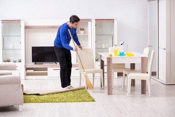 Young man cleaning floor with broom