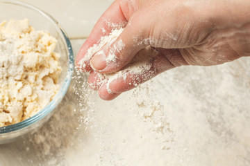 A cook woman holds a flour for pasta in her hand. Raw noodles, pasta