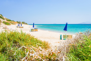 Beaches, Greece, Kos Island, Cap Helona: beautiful holiday setting on a secluded beach with umbrellas on the Greek Aegean Sea with turquoise waters and a picturesque bay and islands in the background
